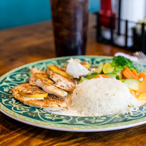 Grilled chicken with lemon slices, white rice, and mixed vegetables on a decorative plate at Georgia Diner.