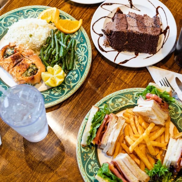 Diner meal with chicken, rice, green beans, chocolate cake, club sandwich, and fries.
