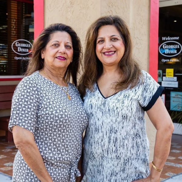 Two women smiling in front of the Georgia Diner entrance, with "Open 24 Hrs" visible.