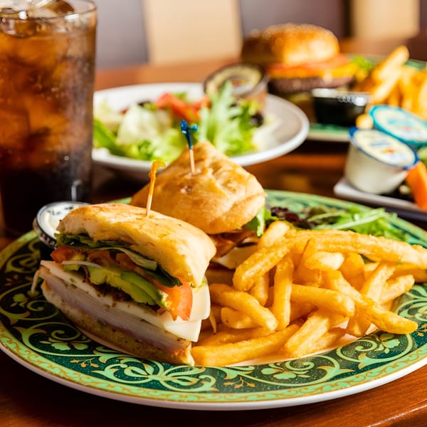 A Georgia Diner sandwich with fries and a drink, with a burger and salad in the background.